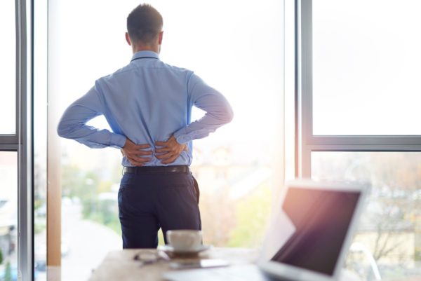 Man with chronic pain holds his lower back