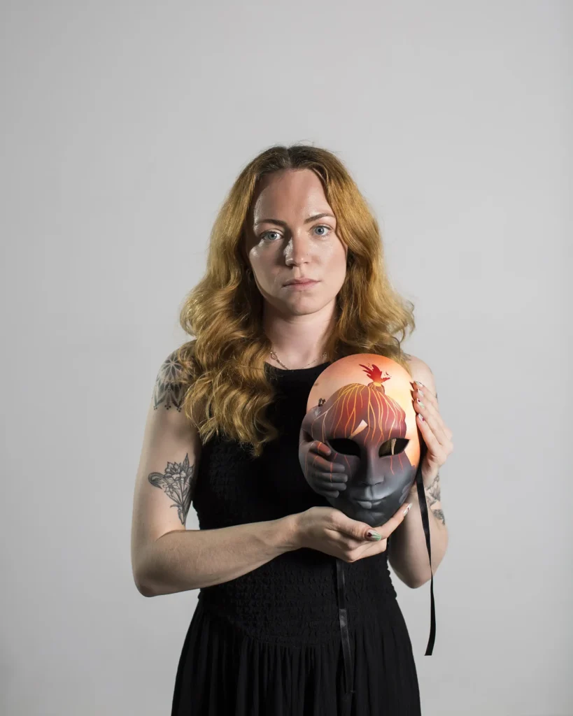 Fran Taylor holding her mask from the art series Pain Unmasked