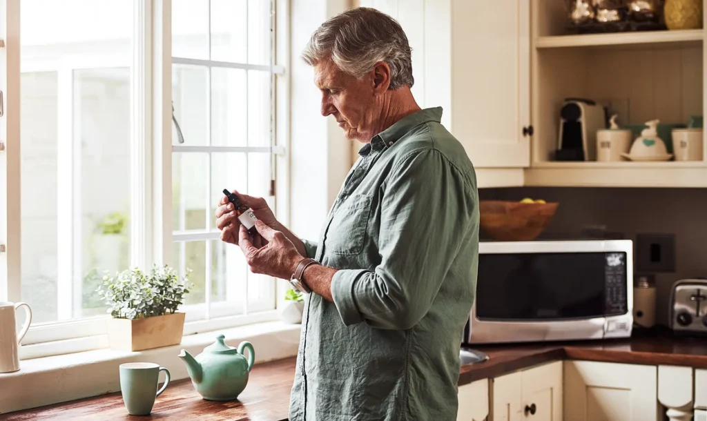 A older man in his kitchen looking at a small, brown bottle of medical cannabis oil