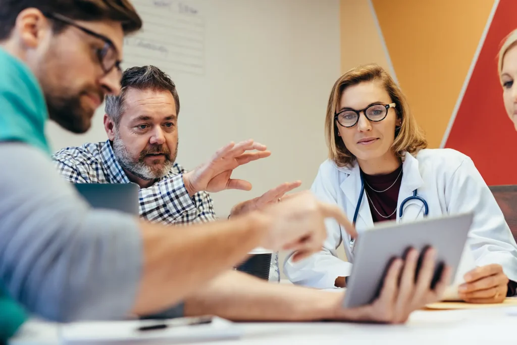 Medical professionals having a meeting, looking into a tablet